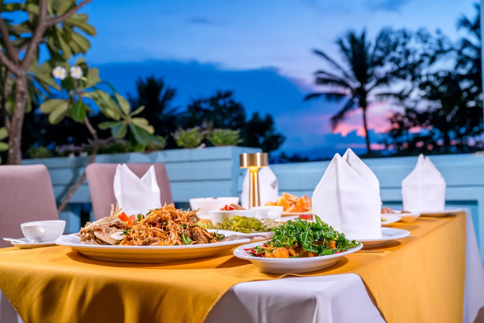 Dinner plates on a riverside terrace table as dusk falls