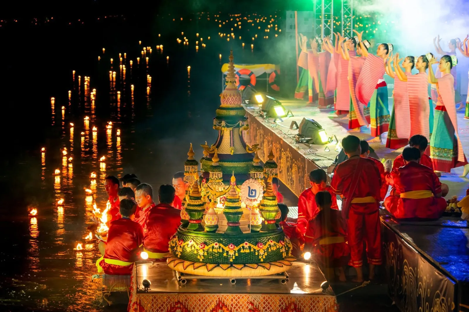 A decorated krathong float surrounded by hundreds of floating lanterns at night