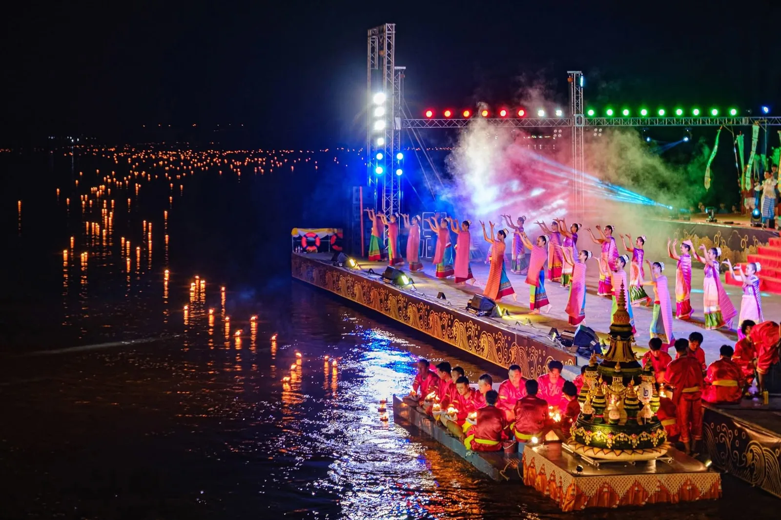 Dancers performing on a riverside stage during Loi Krathong Sai, with lanterns on the water