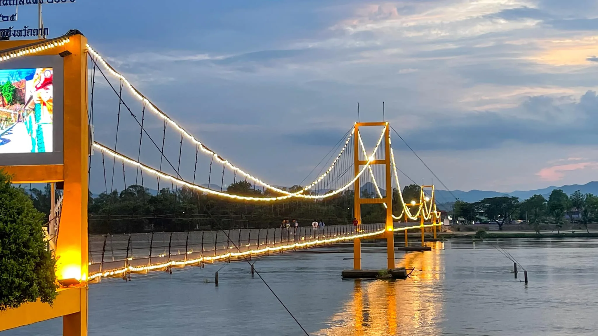 A pedestrian suspension bridge over the Ping River at sunset