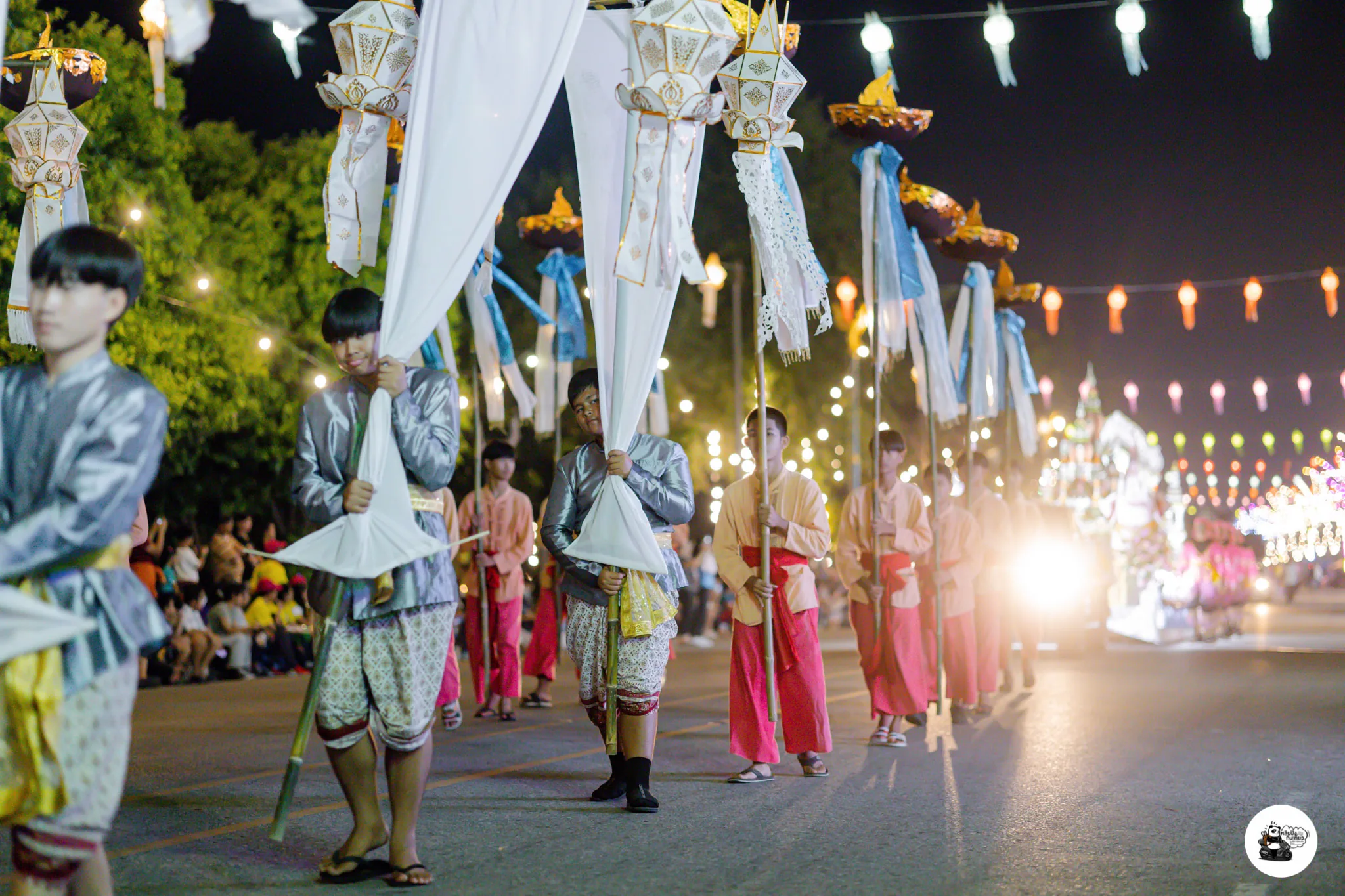 Procession bearers in traditional dress carrying tall lantern staffs