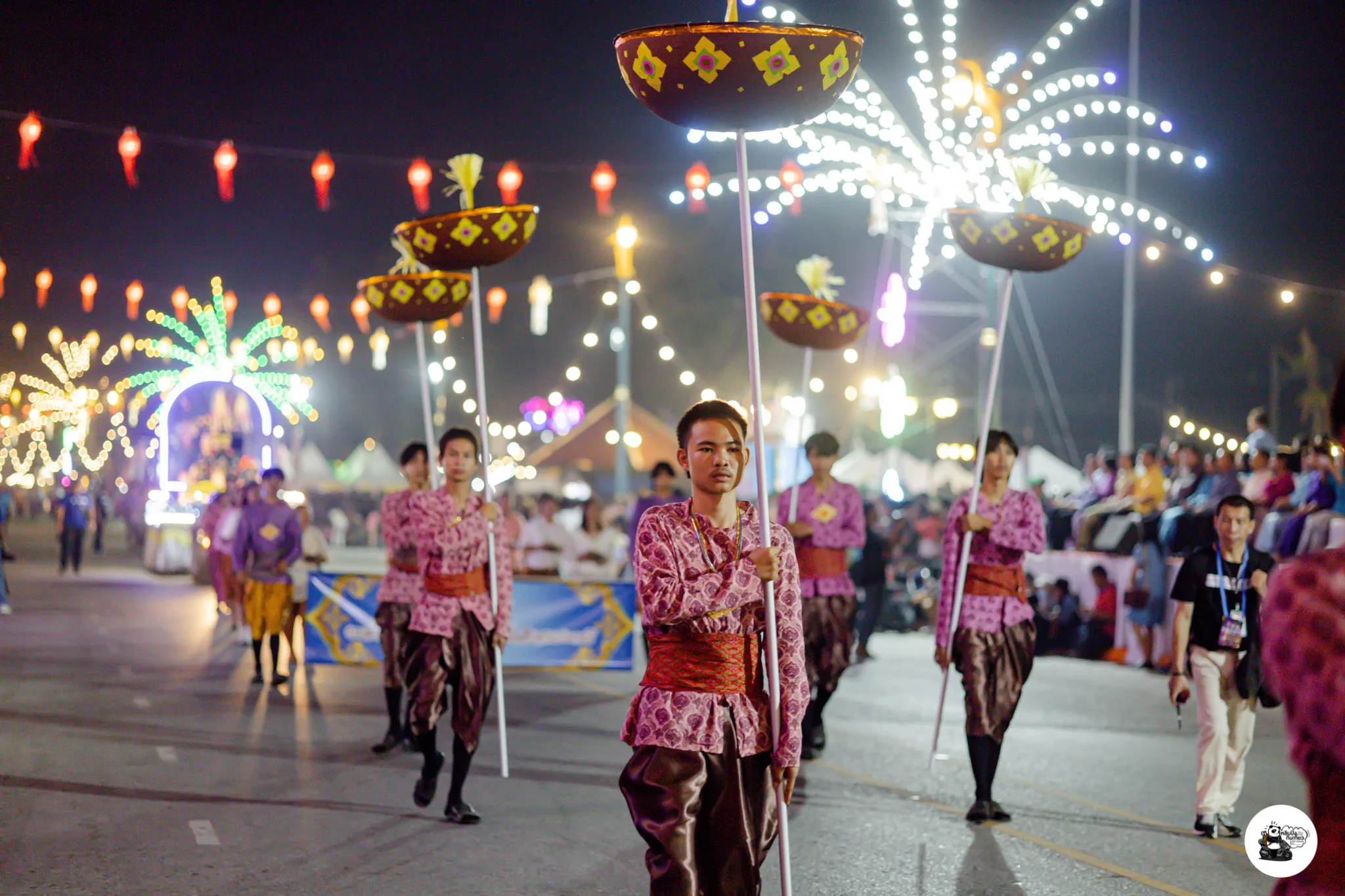 Paddlers in red traditional dress rowing an ornate boat during the procession
